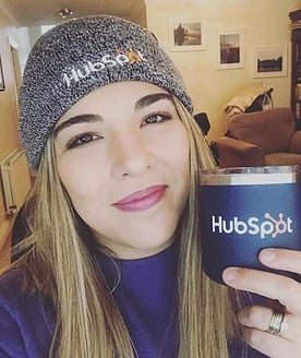 帽子をかぶり、カップを手に持ったHubSpotの従業員